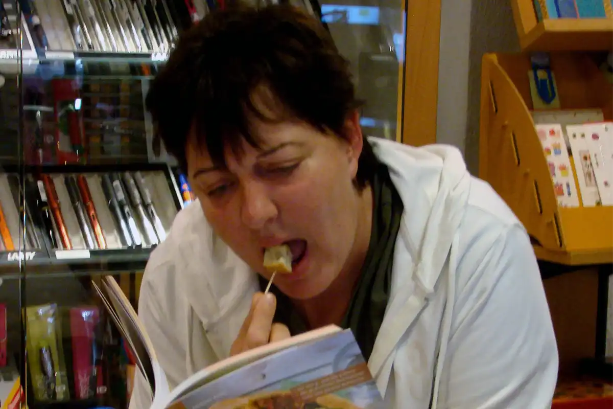 Frau die Brotrinde in den Mund steckt und ein Buch liest