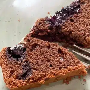 Schokoladenkuchen Brotbackautomat mit Heidelbeeren 4 halbierter Heidelbeeren Schokoladenkuchen mit Kuchengabel auf einem Teller