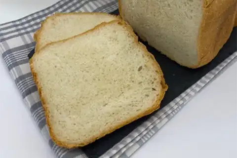 Weißbrot mit Brotbackautomatenform. Aufgeschnittenes Weißbrot auf einem Küchentuch