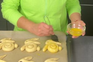 Osterhasen backen aus Hefeteig 12 Hand, die mit einem Pinsel Hefeteighäschen betsreicht