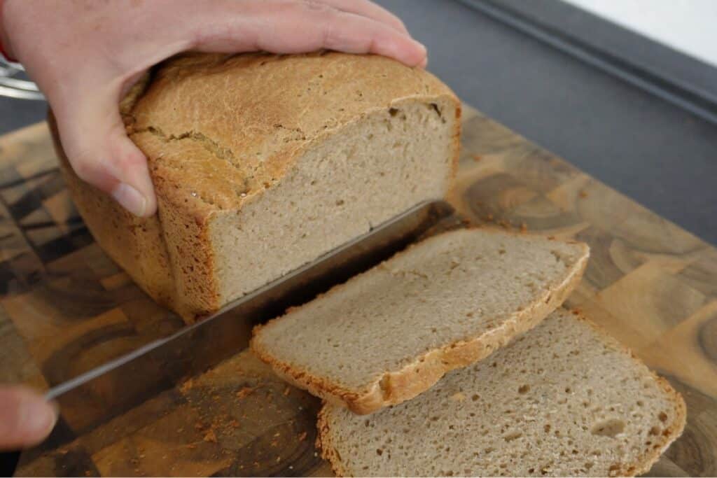 Roggenmischbrot aus dem Brotbackautomaten Rezept. Wird mit einem Messer angeschnitten auf einem Holzbrett.